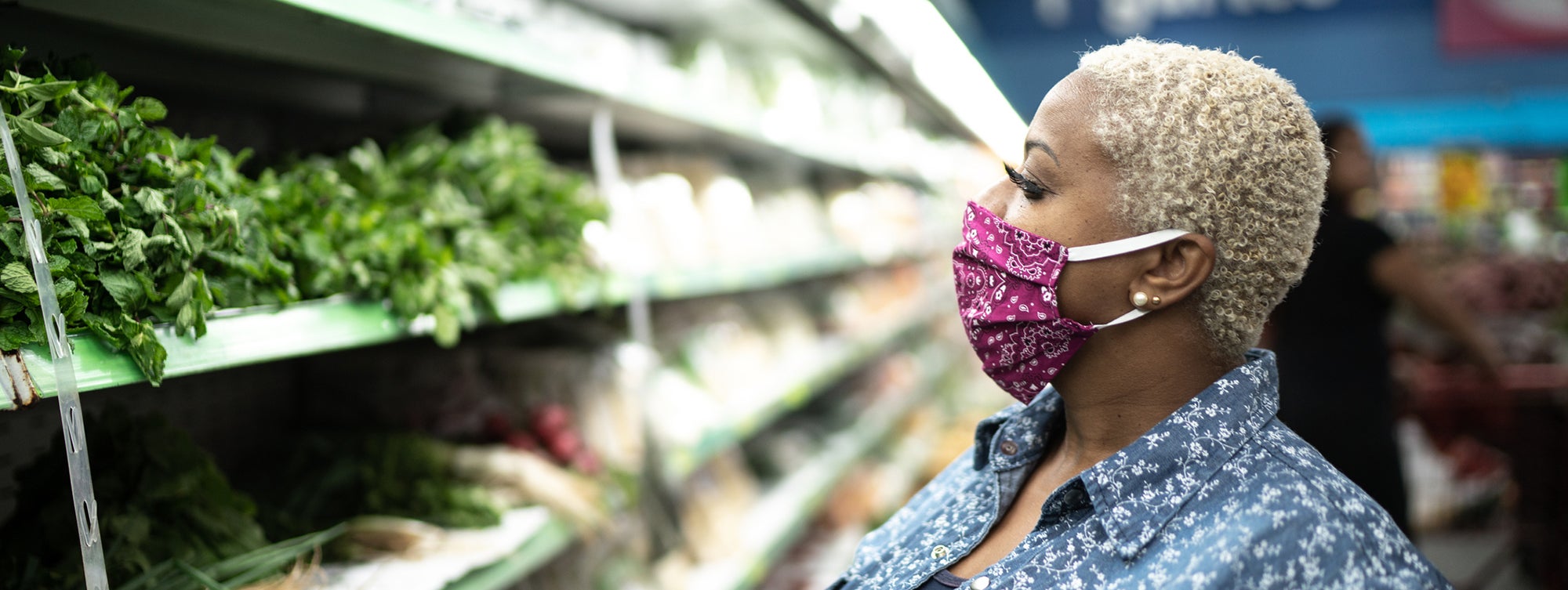 Woman with a cloth face mask shopping at a grocery store